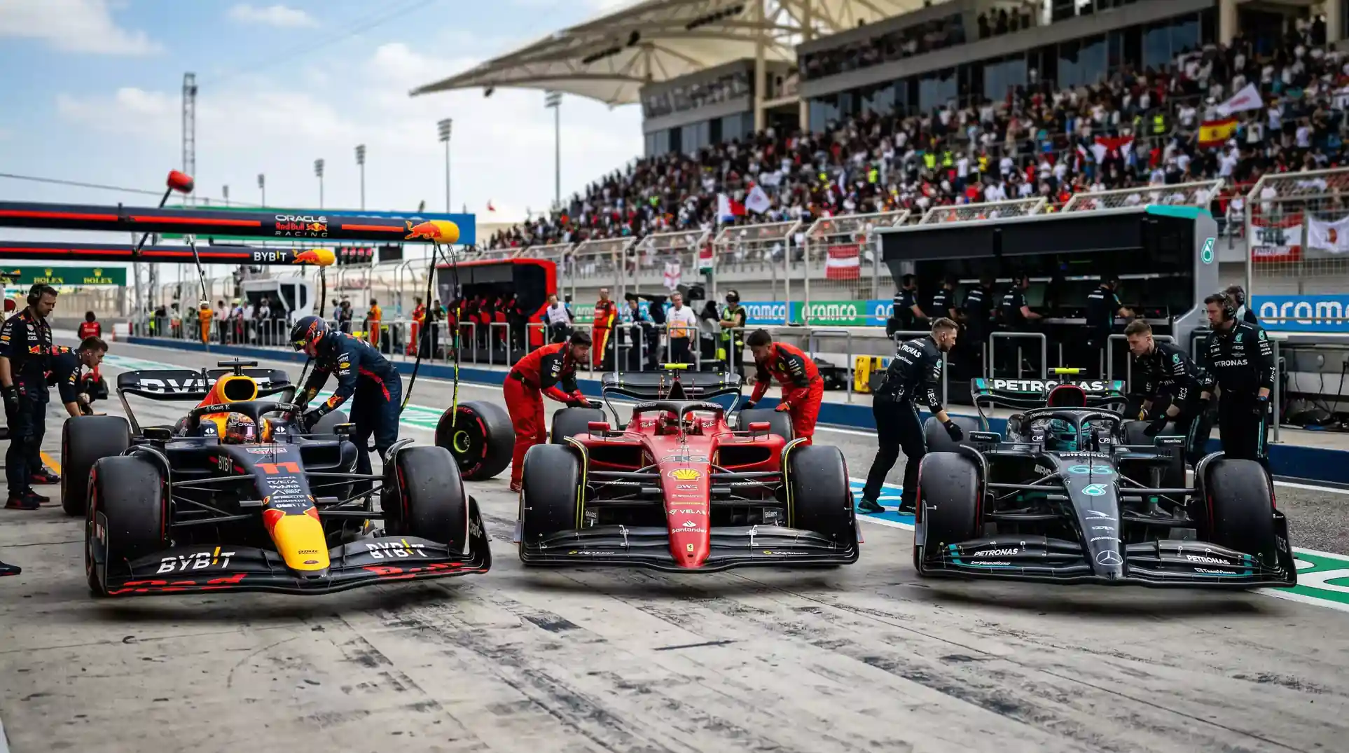 Mehrere Formel 1 Boliden in der Boxengasse nebeneinander aufgereiht vor dem Rennstart